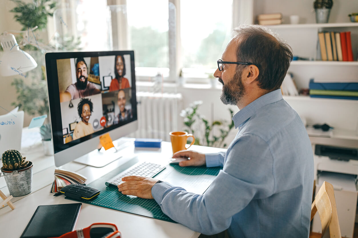 A photo of a man attending a video call in a home office.