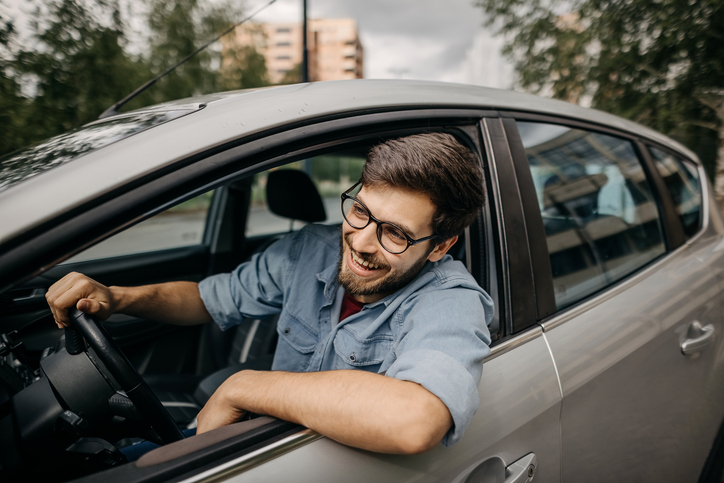 Young man driving car in reverse gear, trying to park the car.