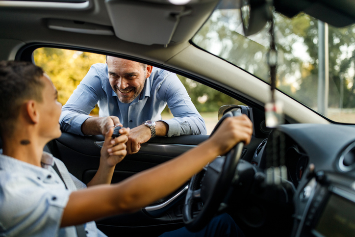 Dad handing car keys off to teenage son.